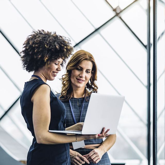 Two businesswomen look together at an open laptop, next to which is an icon labelled 'Modern Work'.