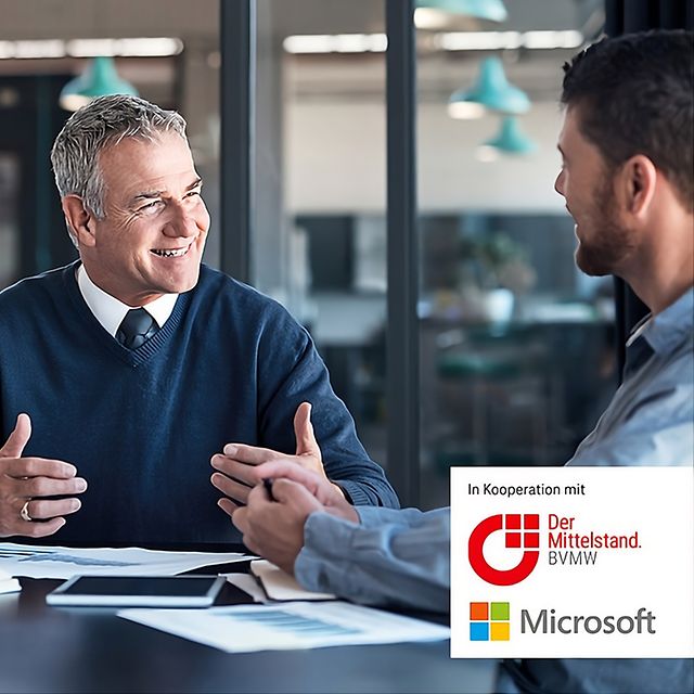 Junge Frau nutzt über das Smartphone Microsoft 365 beim Sitzen am Tisch