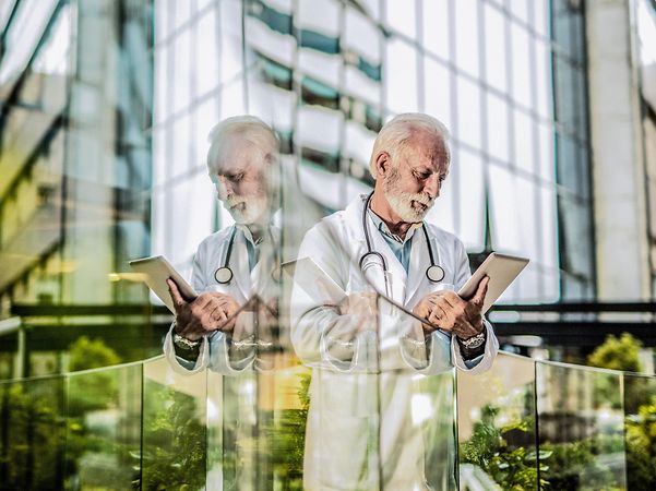 Männlicher Arzt, der im Krankenhaus auf einem digitalen Tablet arbeitet.