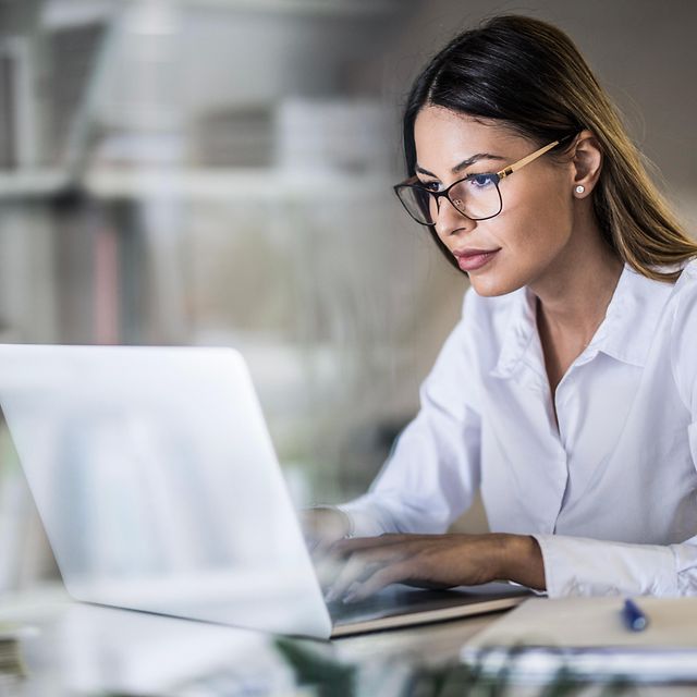 A man is sitting at his laptop in the office, looking up information about Magenta Secure products