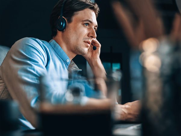 A support staff member wearing a headset is working intently at a computer in the office.
