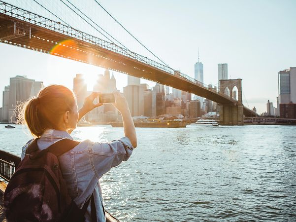 Frau fotografiert Brücke bei Sonnenuntergang.