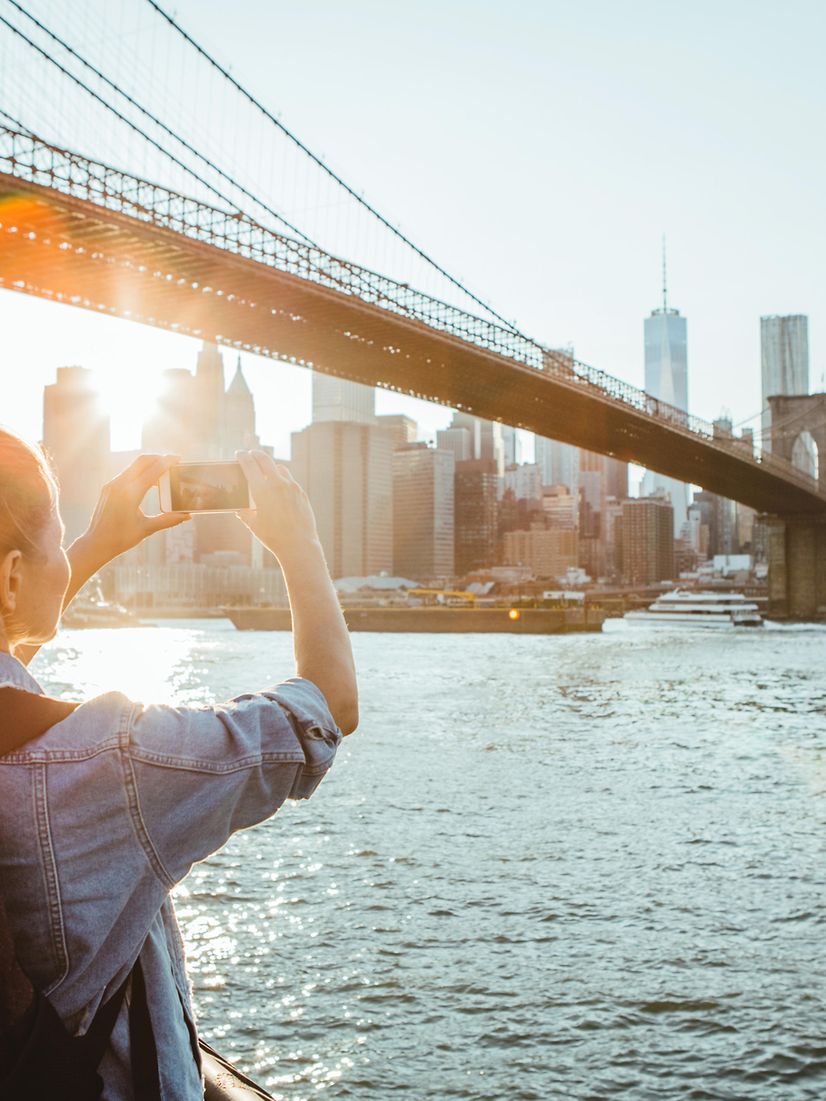 Frau fotografiert Brücke bei Sonnenuntergang.
