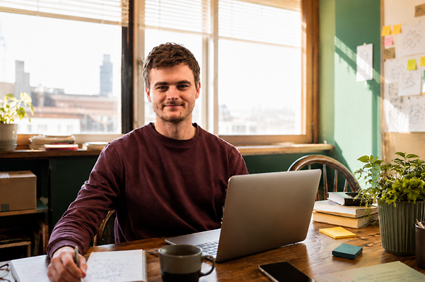 Silas Gründer schaut in die Kamera und sitzt vorm Laptop im Büro