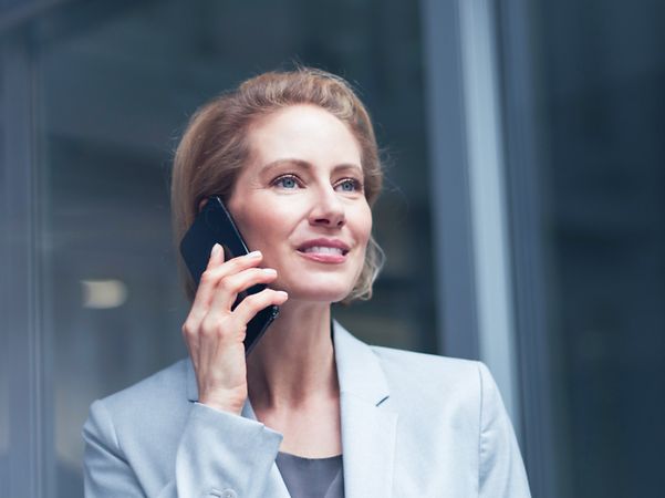Geschäftsfrau telefoniert mit dem handy vor einer Glaswand