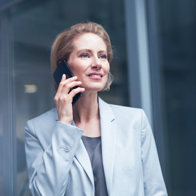 A businesswoman is on her mobile phone in front of a glass wall