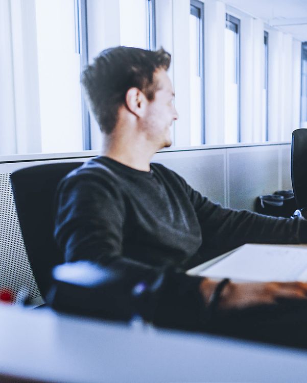 Zwei Männer im Büro nutzen BusinessMail X.400 an ihren Laptops.