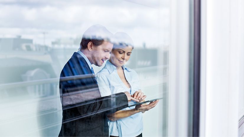 Zwei Erwachsene im Business Outfit betrachten den Telekom Festnetz Tarifberater und die Produktempfehlungen auf einem Tablet.