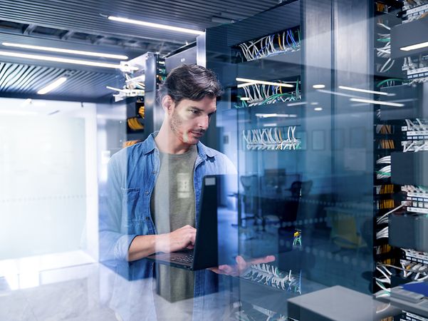 Ein IT-Experte richtet mit seinem Laptop das Webhosting für eine Business Website und Domain ein.