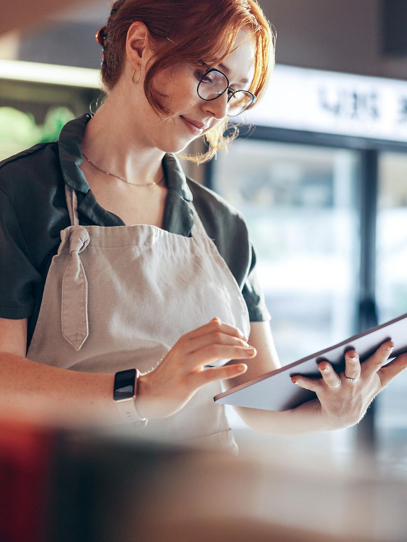 Eine Bäckerin prüft ihren Local Listing Firmeneintrag und ihre Online-Bewertungen am Tablet.