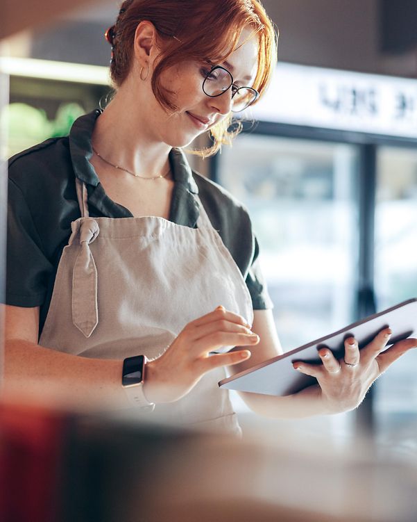 Eine Bäckerin prüft ihren Local Listing Firmeneintrag und ihre Online-Bewertungen am Tablet.