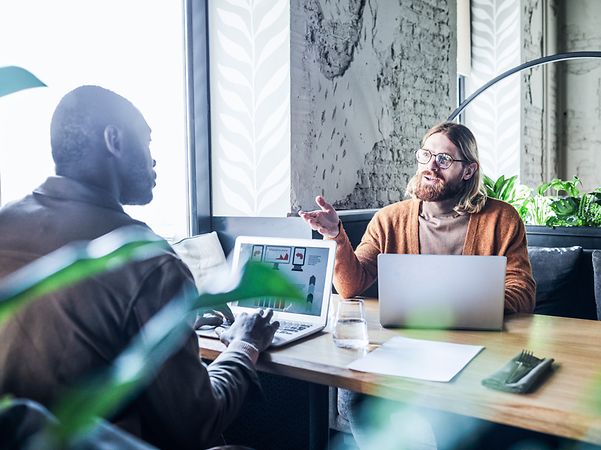 Zwei Menschen sitzen an einem Tisch und unterhalten sich.