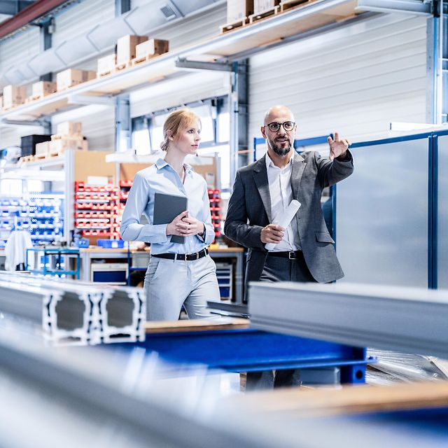 Frau und Mann in Businesskleidung diskutieren in einer Lagerhalle