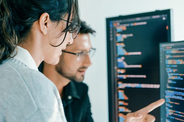 Ein Softwareentwicklungsteam vor zwei Bildschirmen bei der Codeanalyse