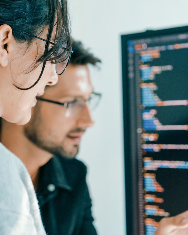 Zwei Kollegen beraten vor einem Bildschirm mit Daten zu den Netzwerk-Lösungen der Telekom