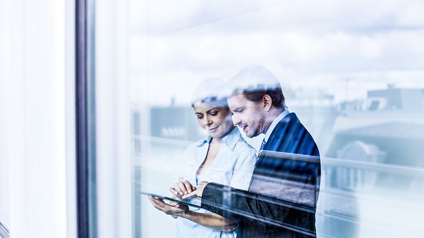 Ein Mann und eine Frau blicken auf ein Tablet mit Jamf Mobile Security & Datenmanagement.