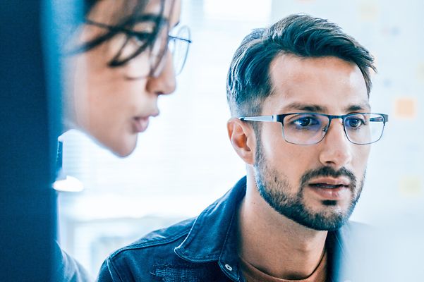 Zwei Mitarbeitende blicken auf den Bildschirm und lesen über Jamf Mobile Security & Datenmanagement.