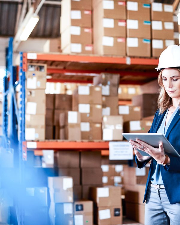 Eine Frau mit Schutzhelm nutzt via Tablet die 5G-Campus Netze zu Datenübertragung auf dem Betriebsgelände