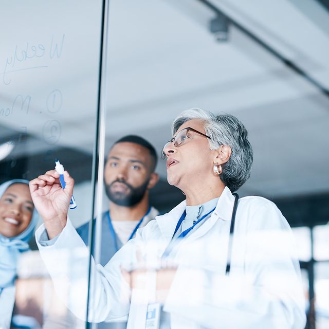 Mehrere Ärzte stehen in einem Krankenehaus vor einem Planungs Board und nutzten die Telematik Lösung