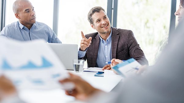 Mehrere Personen sitzen am Tisch und unterhalten sich.