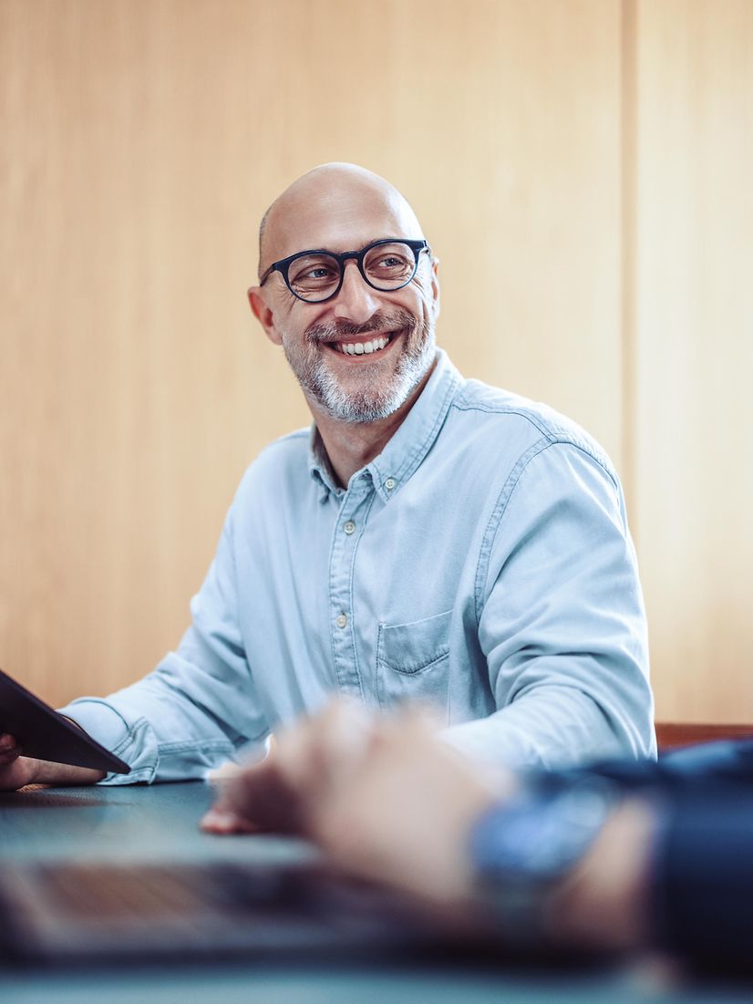 Lächelnder Mann mit Brille nutzt Phone für Microsoft Teams X