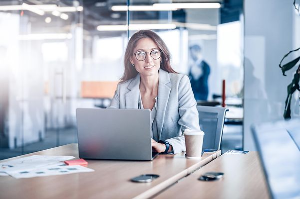 Eine junge Frau schaut von ihrem Laptop auf