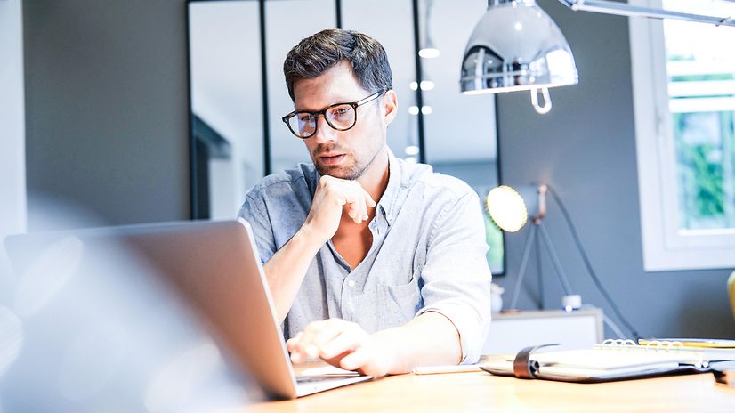 Ein Mann arbeitet in einem hellen Büro am Laptop und nutzt Interactive Voice Response Professional
