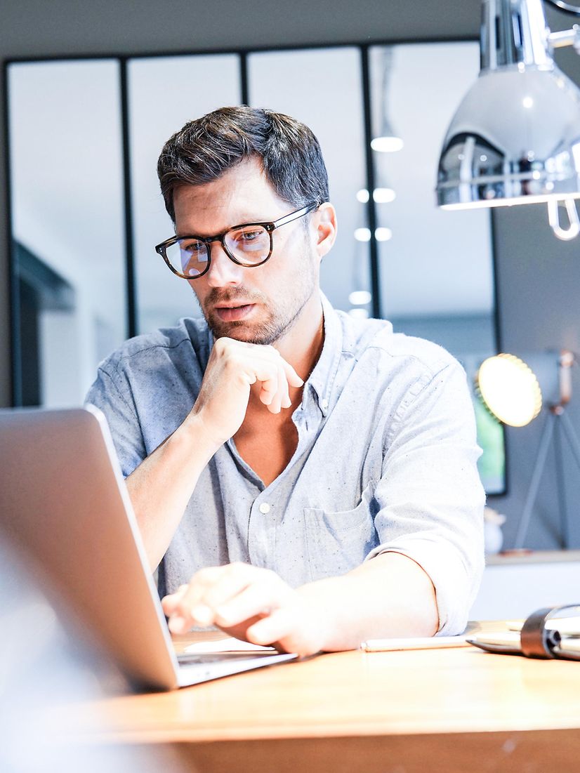 Ein Mann arbeitet in einem hellen Büro am Laptop und nutzt Interactive Voice Response Professional