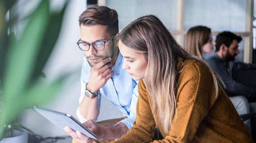 Zwei Personen schauen gemeinsam auf einen Laptop und nutzen Interactive Voice Response Business