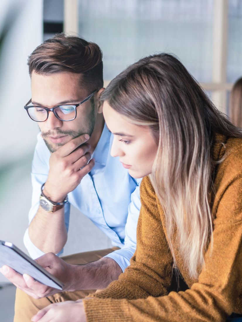 Zwei Personen schauen gemeinsam auf einen Laptop und nutzen Interactive Voice Response Business