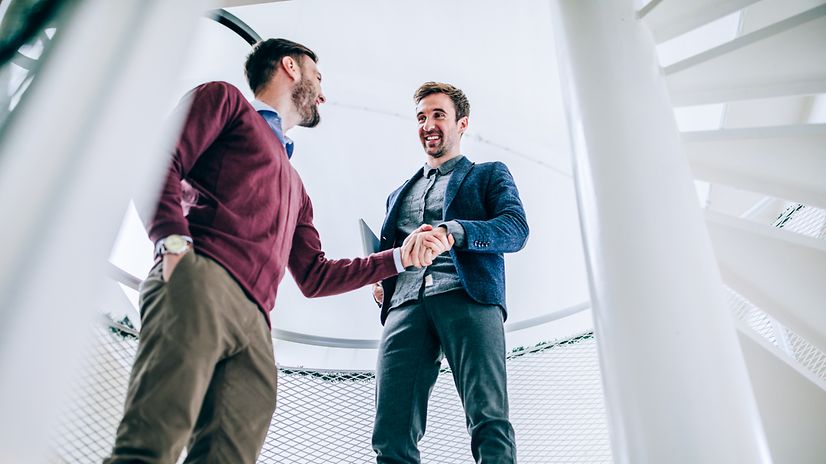 Ein Mitarbeiter gibt einem Kunden die Hand, beide lächeln
