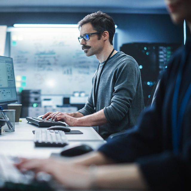 Porträt eines nachdenklichen Ingenieurs, der an einem Desktop-Computer in einer technologischen Büroumgebung arbeitet.