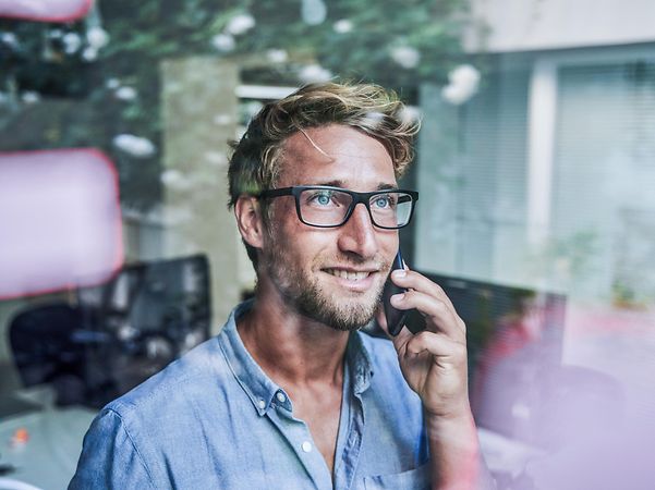 Ein Mann telefoniert und schaut aus dem Fenster.