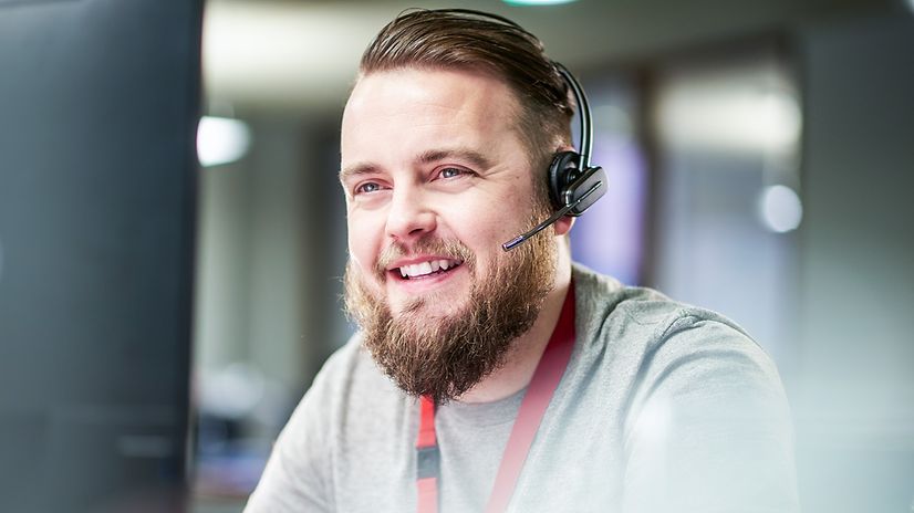 Ein Mann hat ein Headset auf den Ohren und telefoniert.