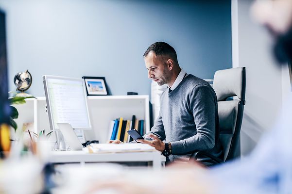 Ein Mann sitzt vor dem Rechner uns schaut auf den Monitor, auf dem ein Zoom X Webinar läuft.