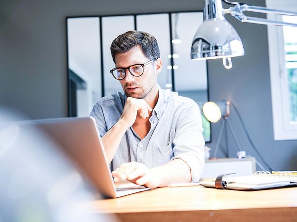 Mann arbeitet am Laptop im Büro und nutzt Microsoft Copilot