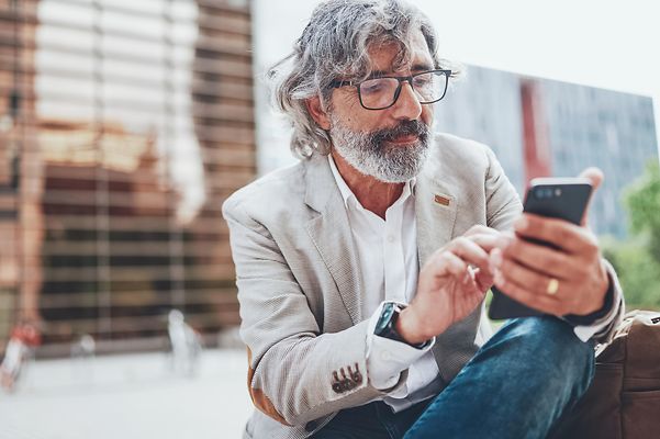 Ein Mann tippt auf sein Handy und bucht sich in DriectNumbering ein. 