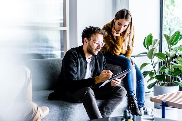 Mitarbeitende im Büro schauen sich einen Download auf einem Tablet an