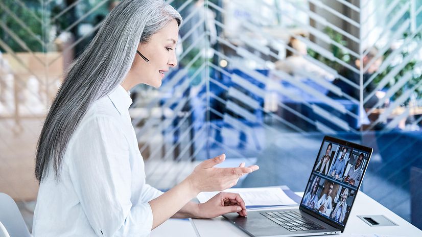 Eine Frau telefoniert vorm Laptop via Headset und informiert über Microsoft Dynamics 365