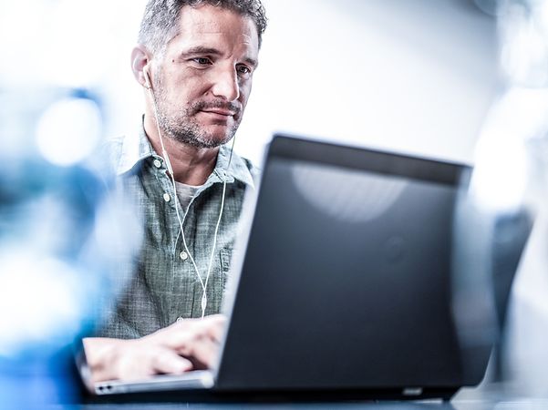 Mann mit Kopfhörern, der am Laptop mit Microsoft Copilot arbeitet
