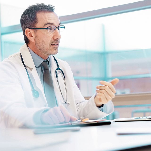 Arzt der in seiner Praxis vor einem Laptop sitzt und die Telematik Lösung der Telekom nutzt