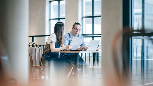 Zwei Personen beraten an einem Besprechungstisch über die Private TelekomCloud für Intersport Voswinkel