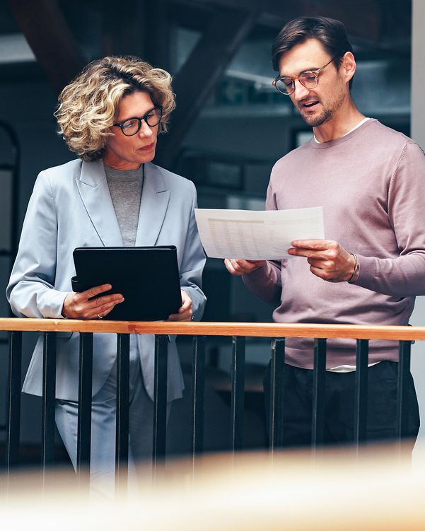 Geschäftsleute lesen gemeinsam ein Dokument. Zwei Fachleute analysieren ein Angebot zur Cloud Infrastructure in einem Büro