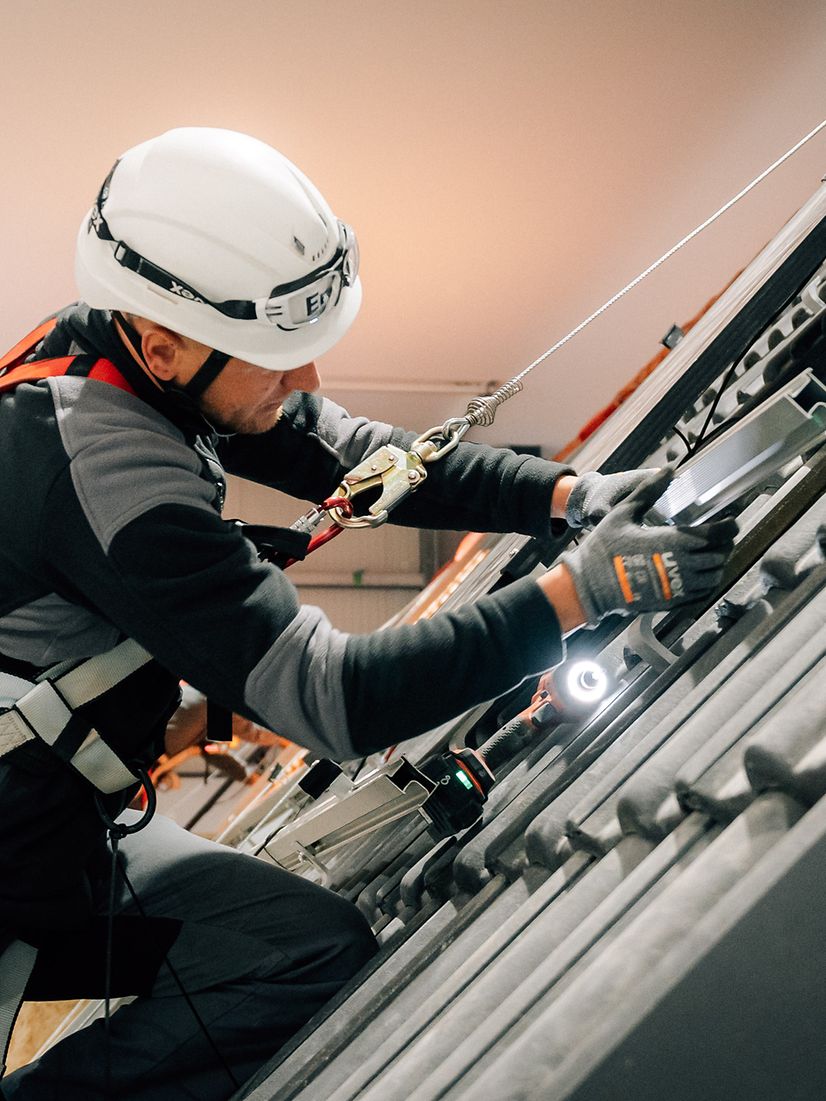 Enpal Mitarbeiter mit Helm und Schutz installiert Solaranlage auf dem Dach