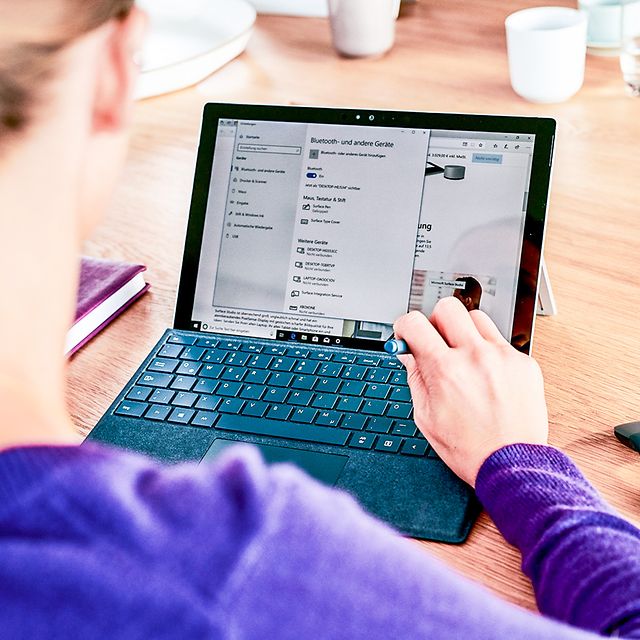 Frau surft auf einem Tablet mit Tastatur und Maus.