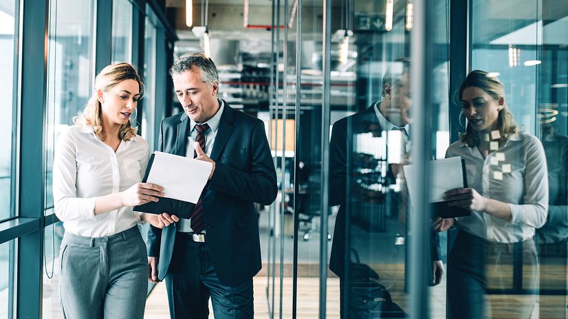 Zwei Kollegen laufen mit einem Tablet über einen Gang im Büro und diskutieren über DevOps-as-a-Service