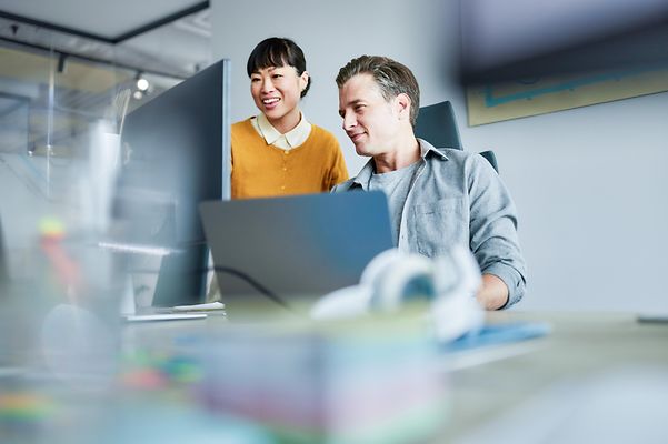 Glückliche Webdesigner arbeiten am PC im Büro.