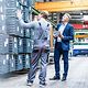 Mitarbeiter in Produktionshalle im Gespräch über Planung und Optimierung – Ausdruck von T Business Gestaltungswille
