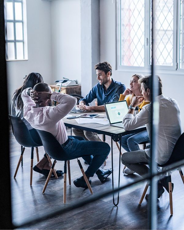 Ein Team sitzt an einem Besprechungstisch, auf dem ein MacBook steht