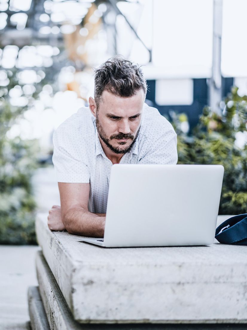 Mann sitzt draußen und arbeitet mit stabiler mobiler Verbindung durch Mobile Optimization Pro.